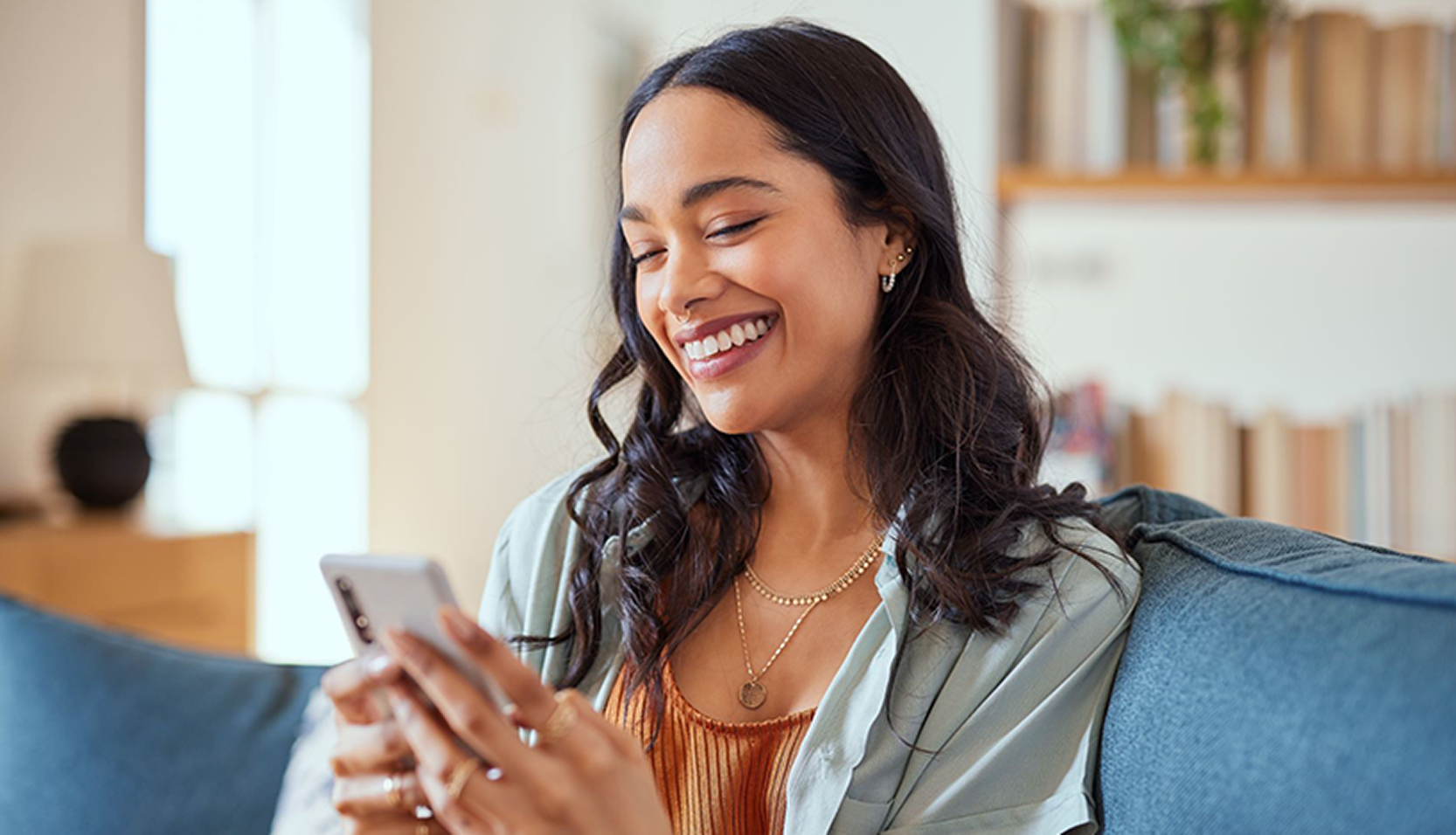 Person smiling as they use a smartphone while relaxing at home