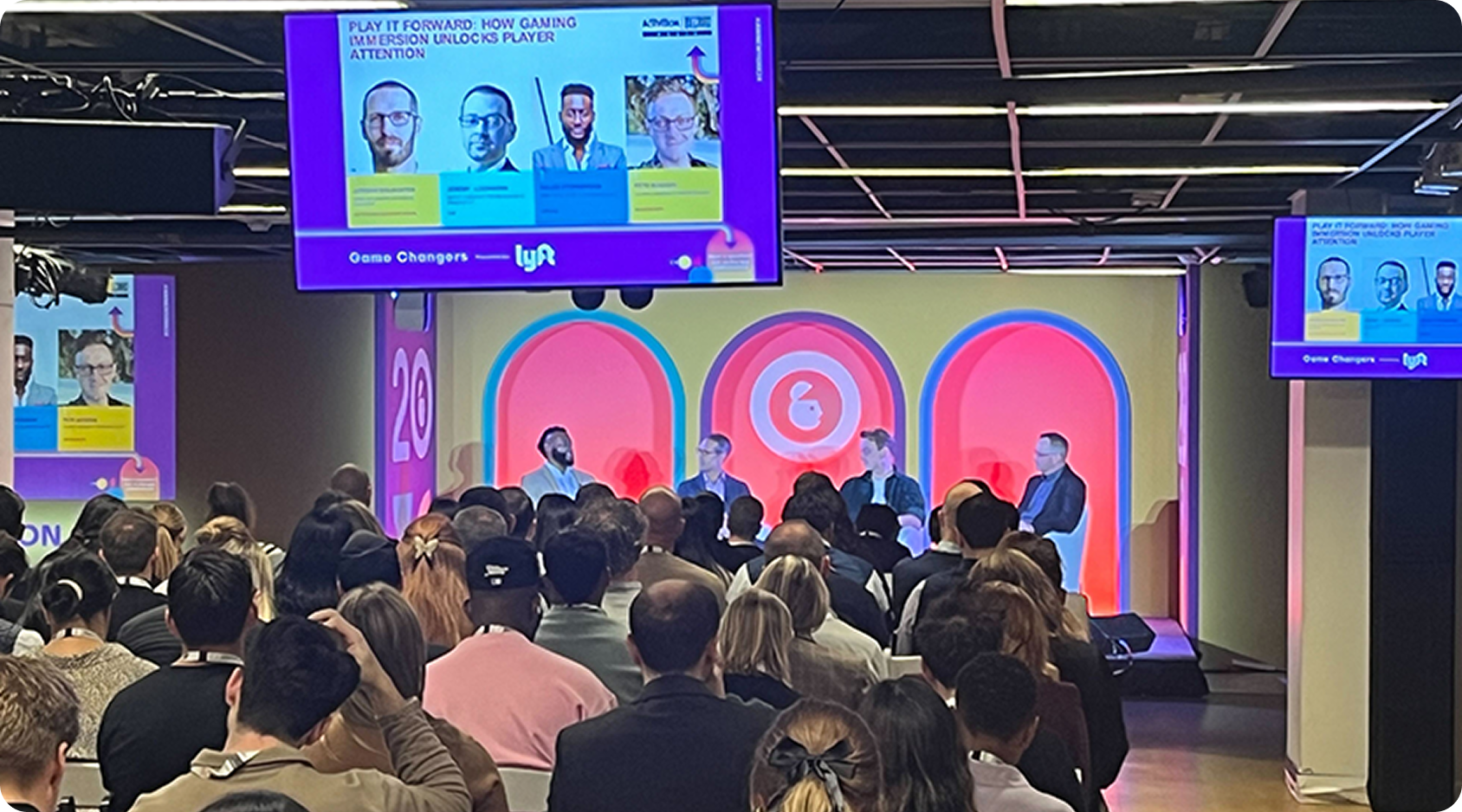 Large audience seated and watching a panel discussion at Advertising Week New York, with event screens showing speaker details.