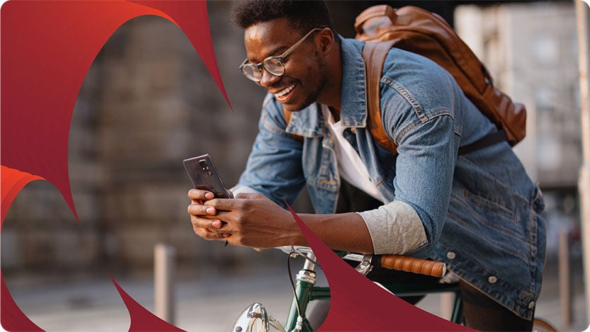 A person leaning on a bicycle while looking at a smartphone.