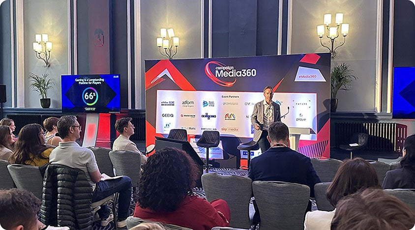 Chris Bailes presenting at Media360 in front of a screen showing gaming audience insights.
