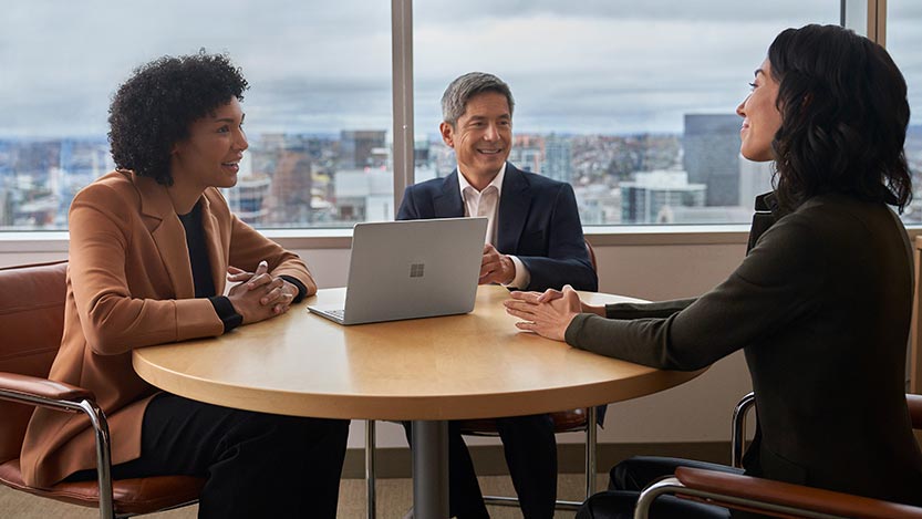 Three people sitting around a table during a work meeting