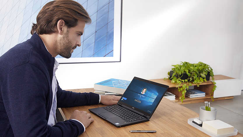 A man sitting at a desk works on a laptop.