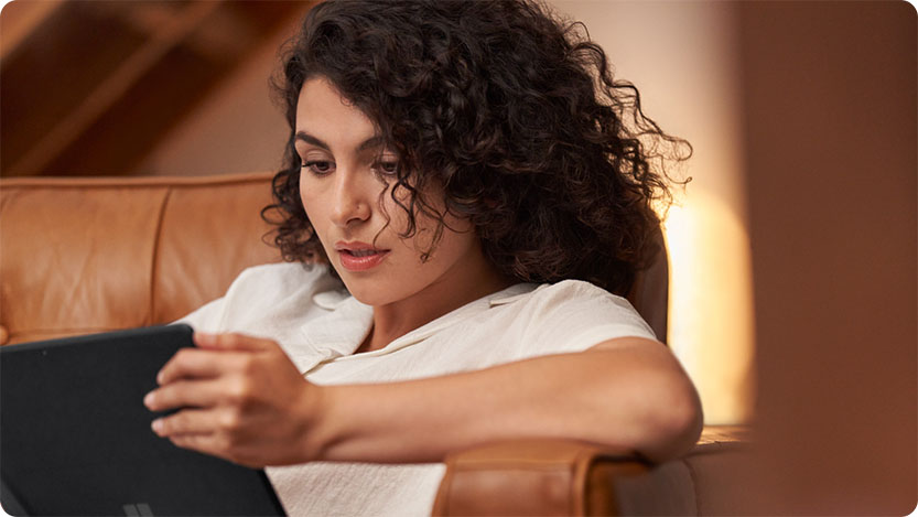 Personne allongée sur un canapé utilisant une tablette.