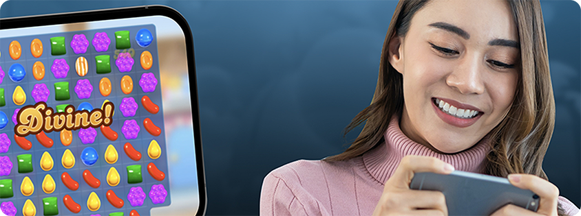 Woman smiling while playing a mobile game, shown alongside a close-up of the Candy Crush Saga game screen.