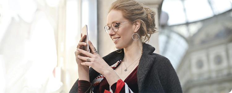 A person holding shopping bags and looking at a phone.