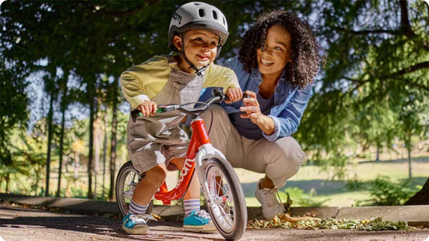 Child learning to ride red balance bike