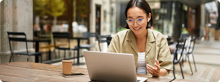 Person using a laptop at an outdoor café, browsing content online.