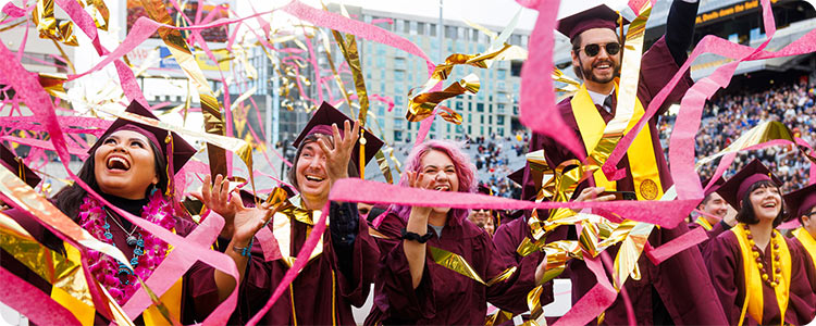 Happy university students celebrating on graduation day with graduation gowns.