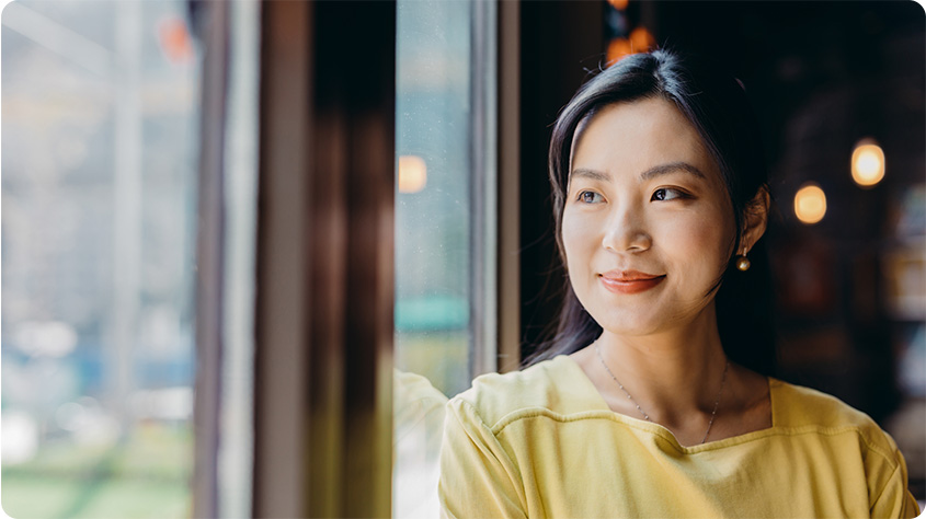 Portrait of a confident Asian businesswoman looking out a window.