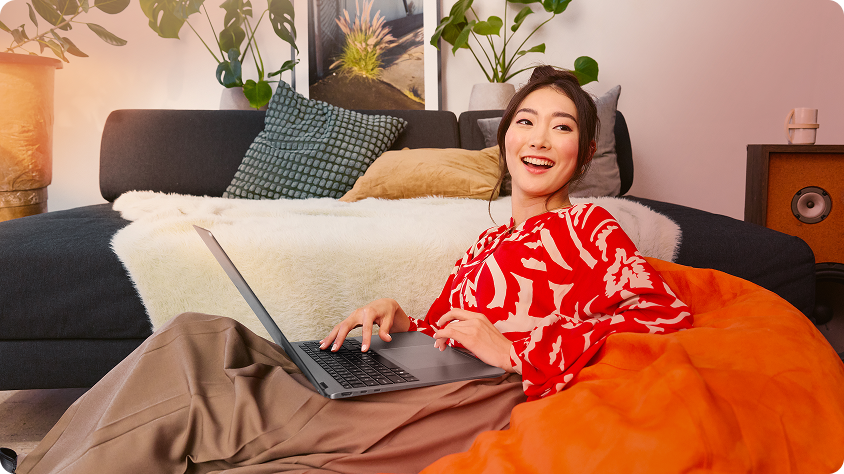 Photograph of young adult female sitting inside with laptop.